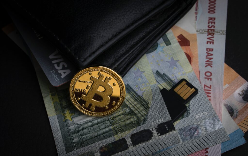 Grafika Bitcoin na tle portfela z kartami kredytowymi i walutami fiducjarnymiPhoto by Aleksi Räisä on Unsplash